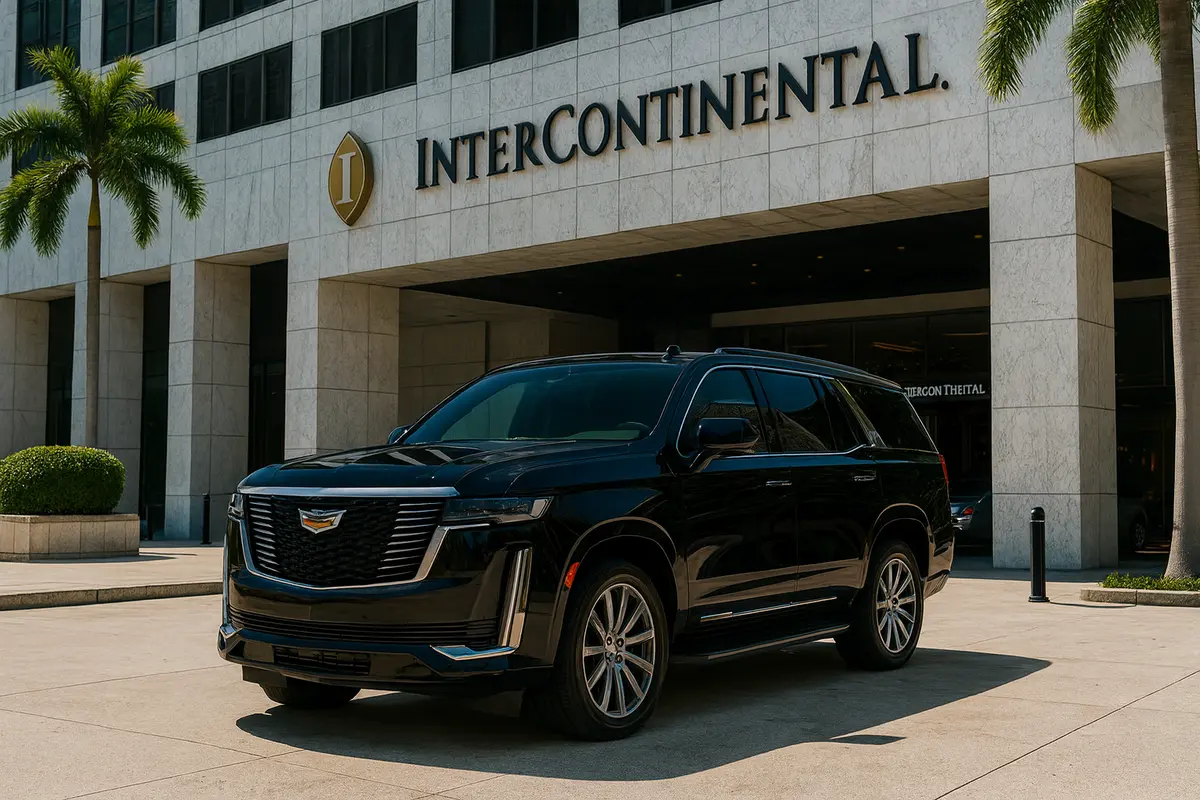 Black Cadillac Escalade parked in front of the InterContinental Hotel entrance in Miami, framed by palm trees and the hotel’s grand facade.